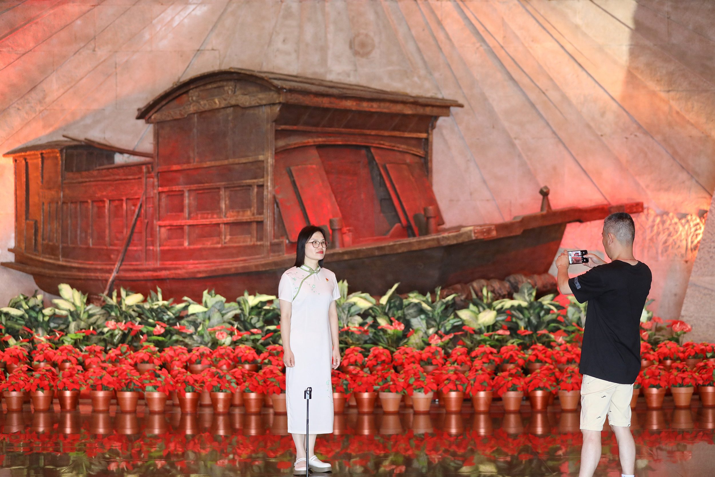 2025年6月24日，浙江嘉興，游客在南湖革命紀(jì)念館與紅船雕塑合影。（圖片來源：視覺中國）